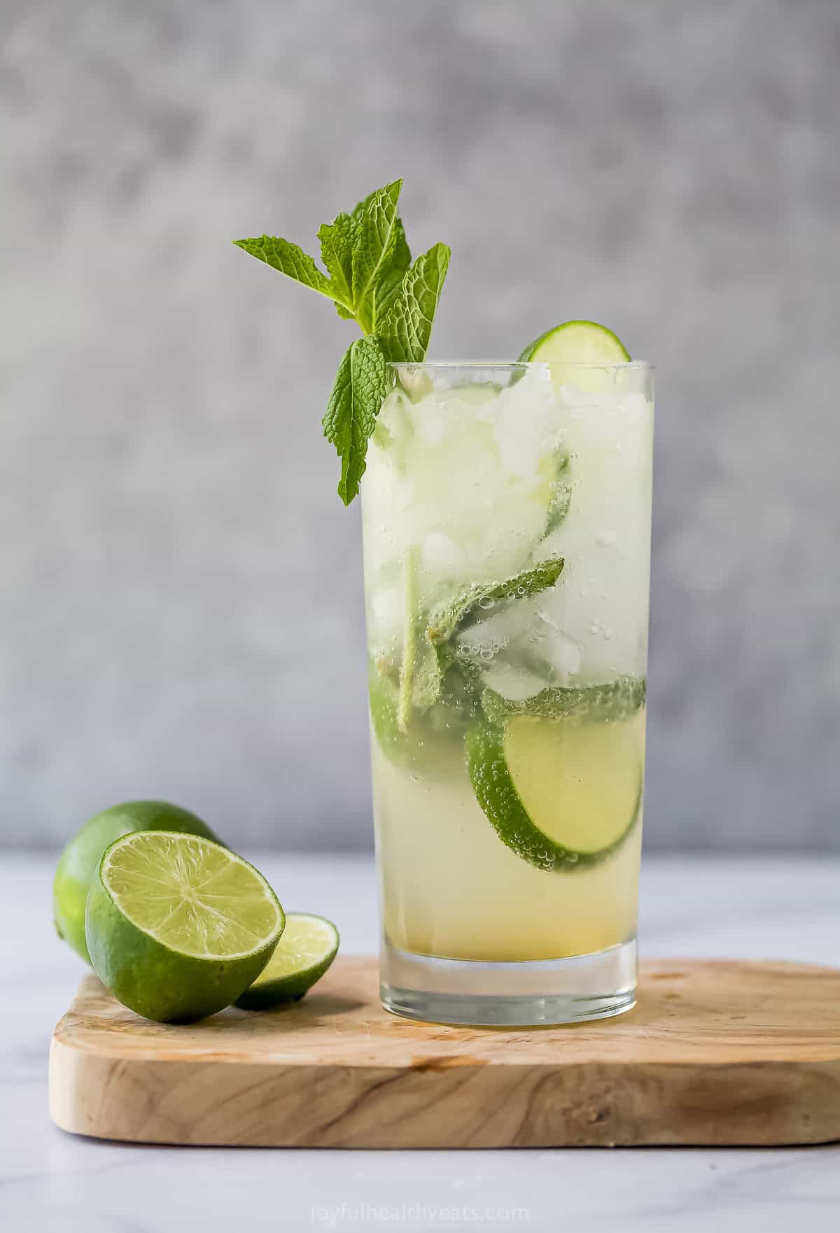 This Nojito recipe has everything you love about the original, minus the alcohol! Fresh mint, lime and sparkling water make it so refreshing. Nojito in glass on wooden cutting board with cut lime
