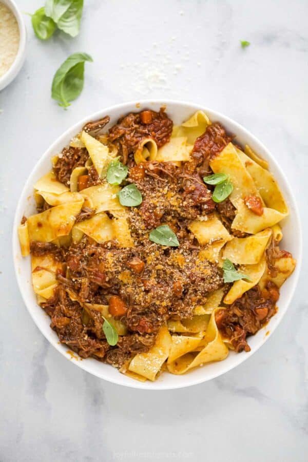 Overhead view of braised short rib ragu served over pappardelle in bowl