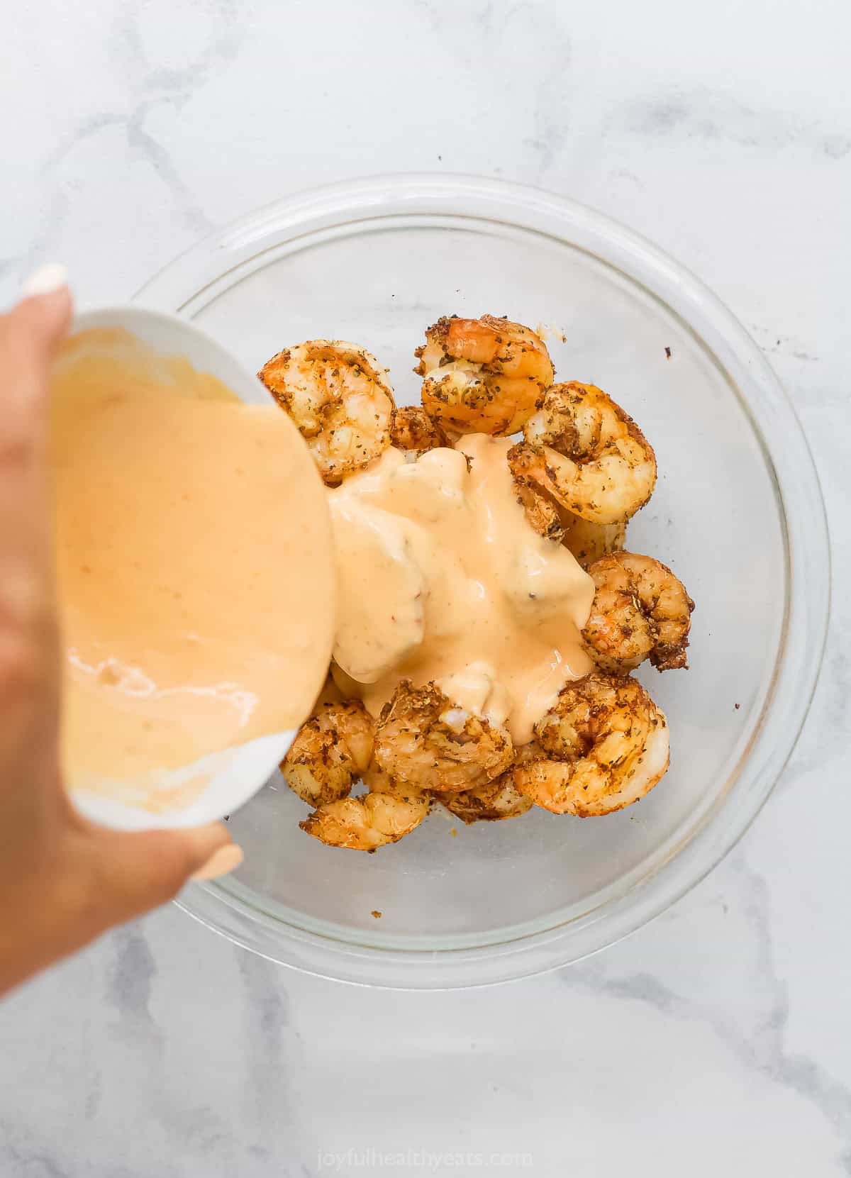 The air fryer makes this crispy Bang Bang Shrimp recipe super easy and lighter, and a creamy, spicy sauce makes it irresistible! Pouring bang bang sauce over shrimp