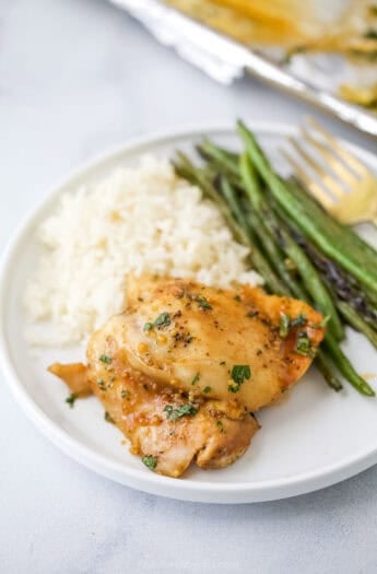 Honey garlic slow cooker chicken thigh on plate with roasted green beans and white rice