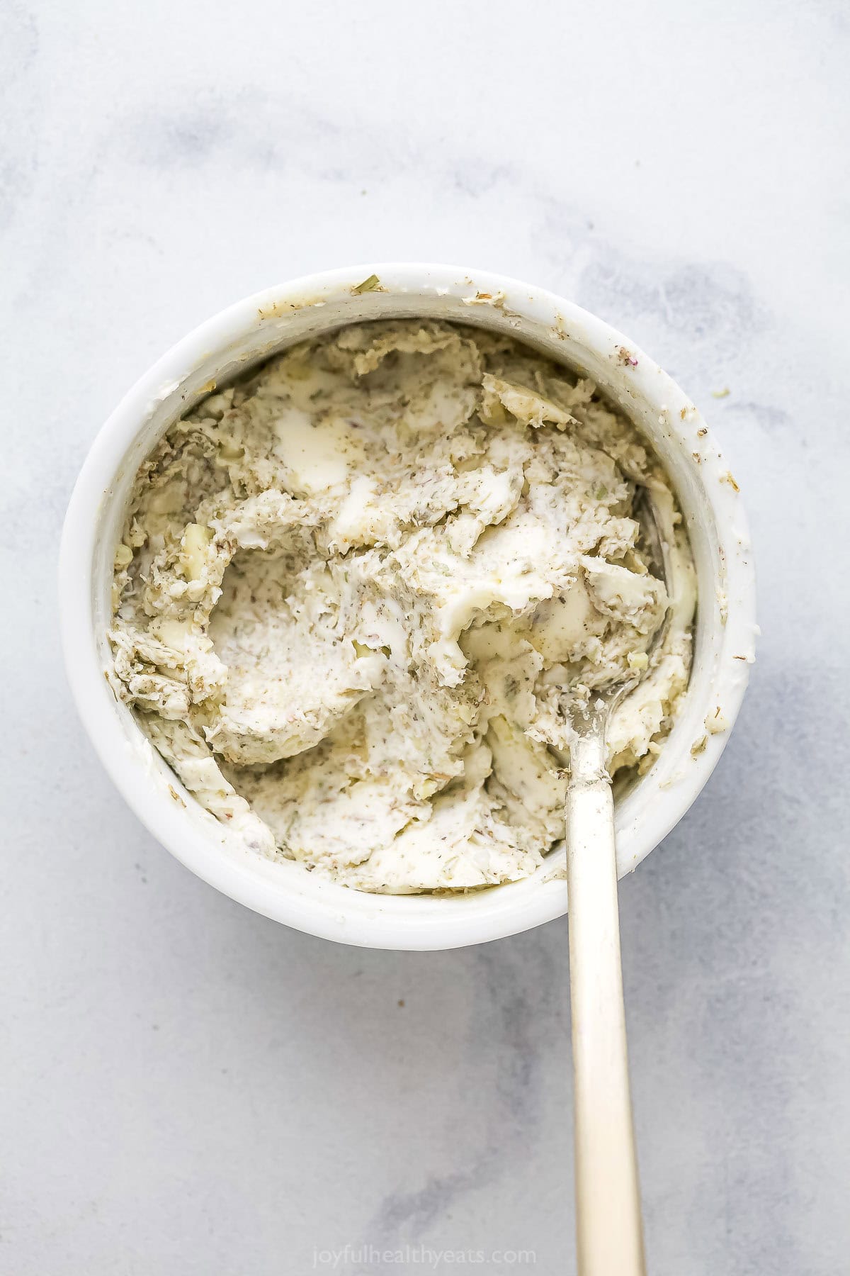 This Garlic Herb Roasted Turkey Leg recipe is juicy and succulent, with an herbed garlic butter rub that adds SO much flavor. The best! Garlic herb butter in bowl with spoon.