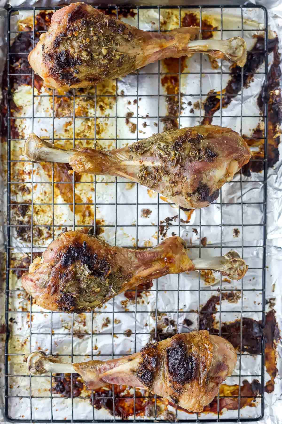 This Garlic Herb Roasted Turkey Leg recipe is juicy and succulent, with an herbed garlic butter rub that adds SO much flavor. The best! Overhead view of garlic herb roasted turkey legs on wire rack.
