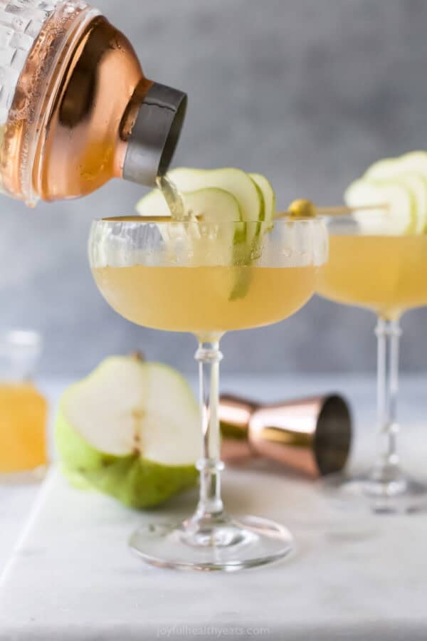 With the sweet, delicate flavor of pears and elderflower, this Pear Martini tastes fancy but it’s super easy to make at home! Pouring pear martini into glass.