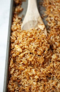 Wooden spoon scooping crispy rice from sheet pan.