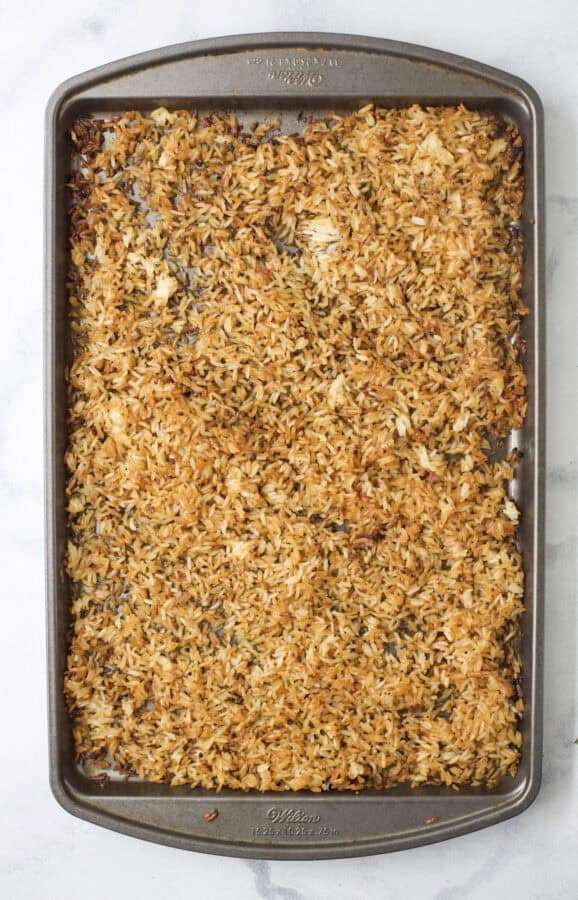 This viral TikTok sheet pan crispy rice is tossed in savory sauce and baked until golden for the perfect addition to salads, bowls and more! Rice spread onto sheet pan.