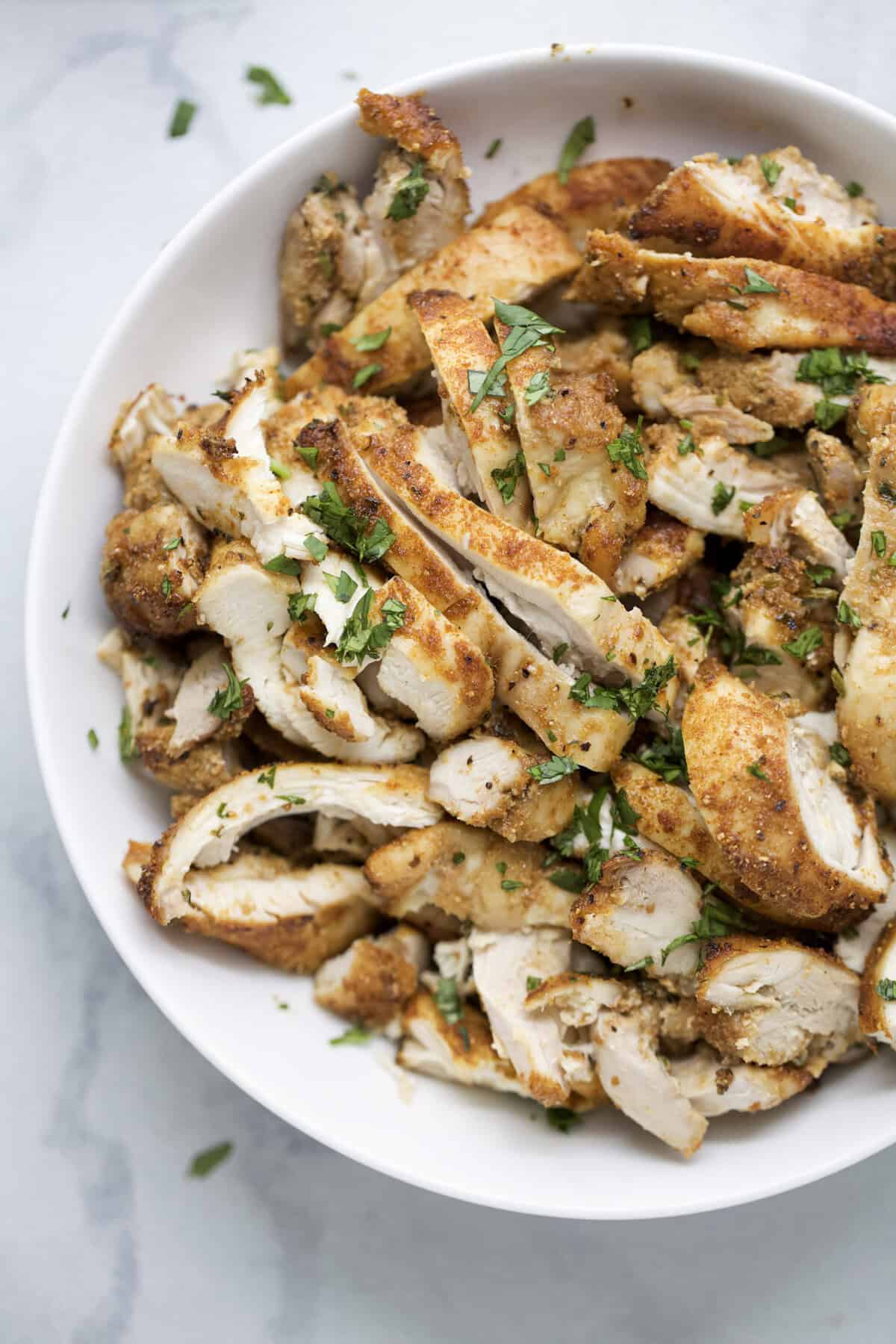 Sliced air fried chicken thighs in bowl.