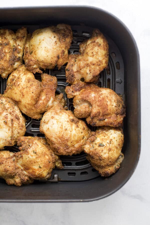 Crispy chicken thighs in air fryer basket.