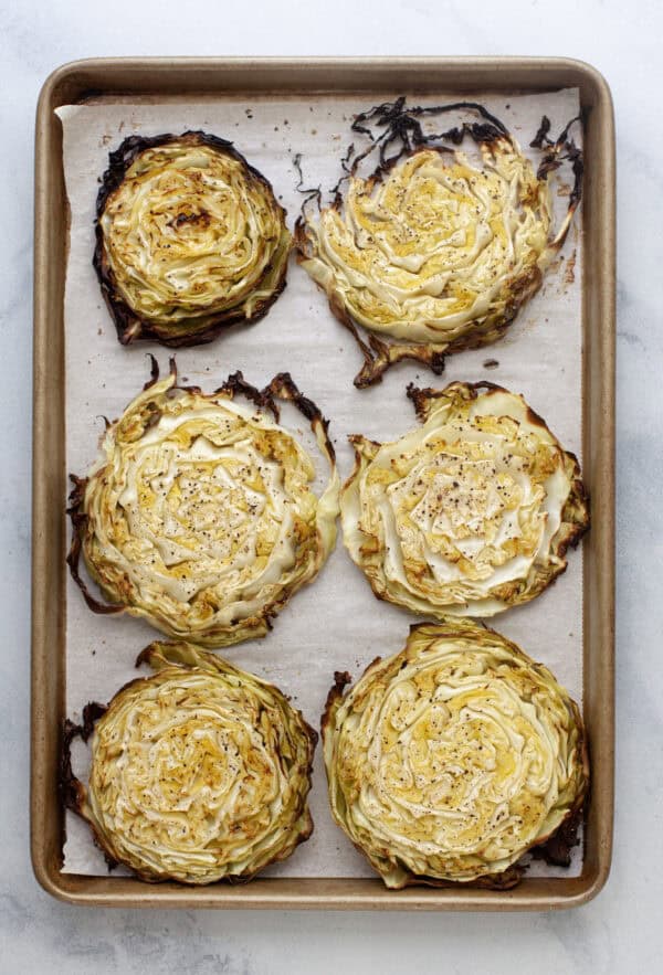 Blistered cabbage steaks on parchment lined sheet pan.