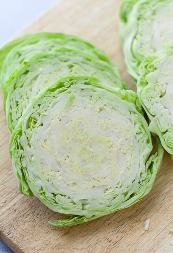 Sliced cabbage steaks on cutting board before cooking.