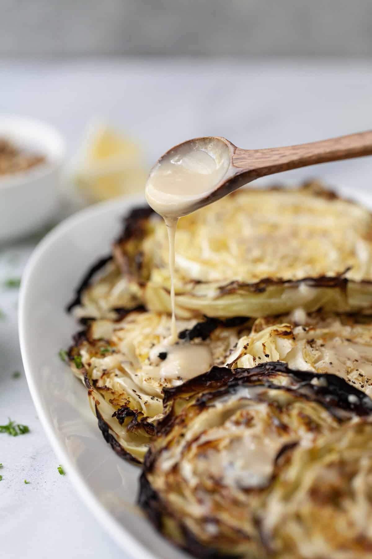 Drizzling maple tahini on blistered cabbage steaks.