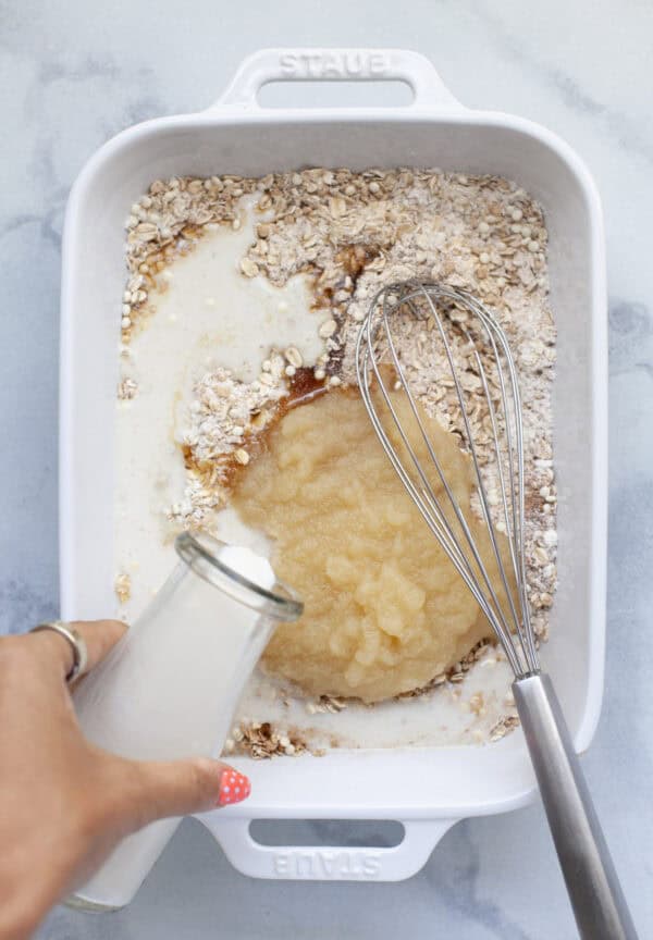 Pouring milk into baking dish with oats and applesauce