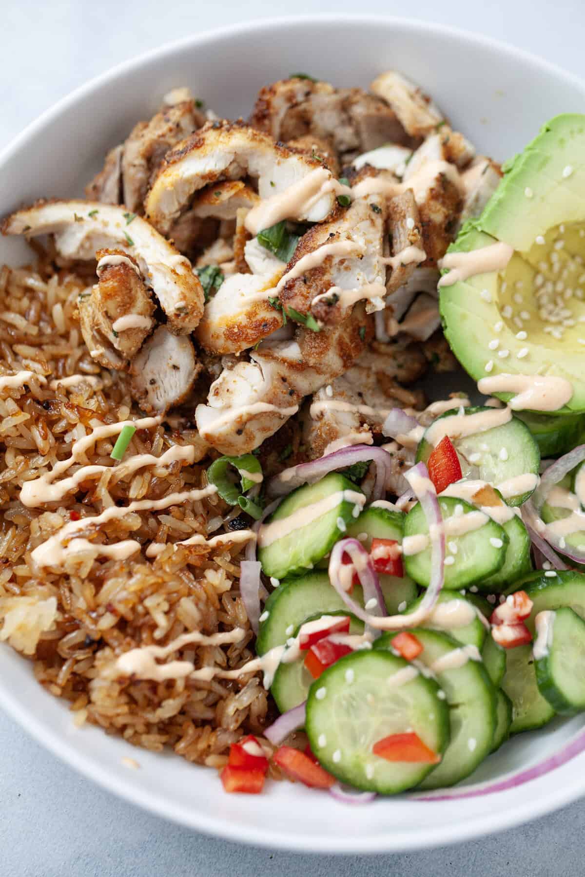 Crispy chicken rice bowl with spicy mayo drizzled over top.