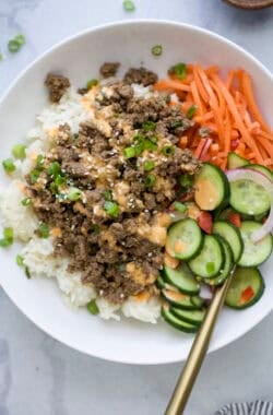 High protein Korean beef bowl with cucumber salad, rice, and carrots.