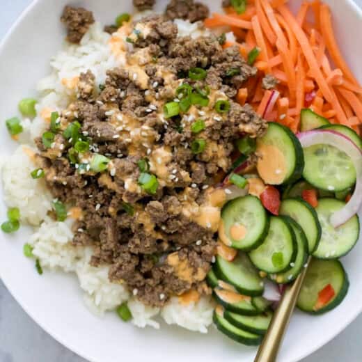 High protein Korean beef bowl with cucumber salad, rice, and carrots.