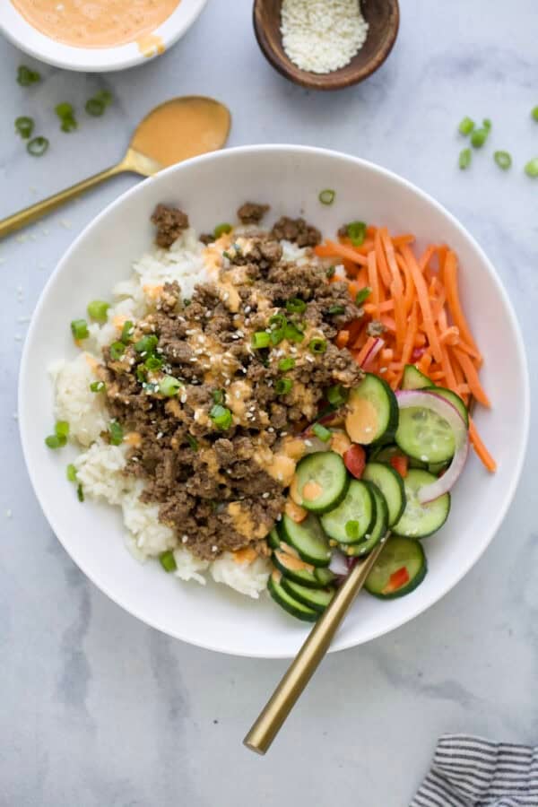 Korean beef bowl with rice, cucumbers, and carrots.