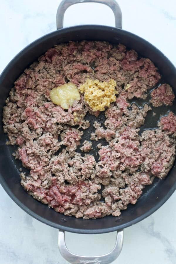 Ground beef in skillet with garlic and ginger.