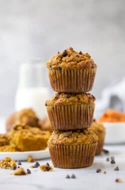 3 chocolate chip pumpkin protein muffins stacked on countertop.