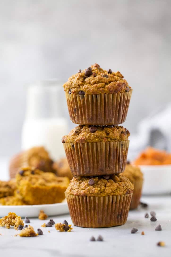 3 chocolate chip pumpkin protein muffins stacked on countertop.