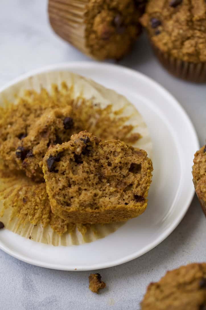 Pumpkin protein muffin torn in half on plate to show fluffy texture.